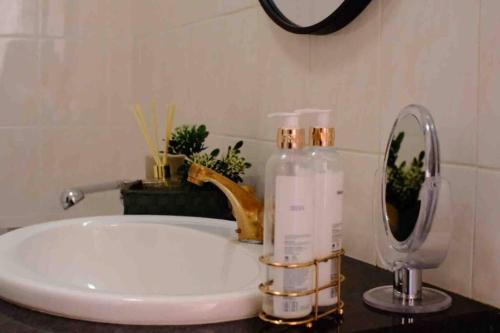 a bathroom sink with a bottle of soap and a mirror at Perfectly located beauty in secure Estate in Sandton