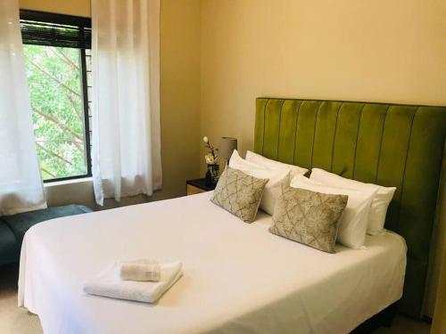 a bedroom with a large white bed with a green headboard at Perfectly located beauty in secure Estate in Sandton
