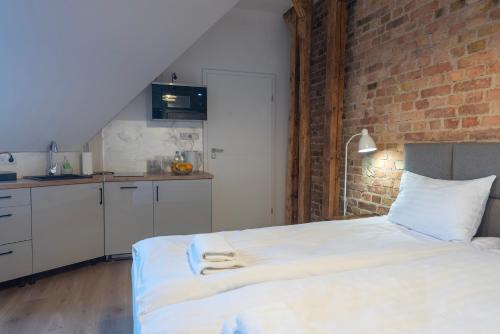 a bedroom with a white bed and a brick wall at PROVENIR HOME KWIATOWA 5 in Poznań