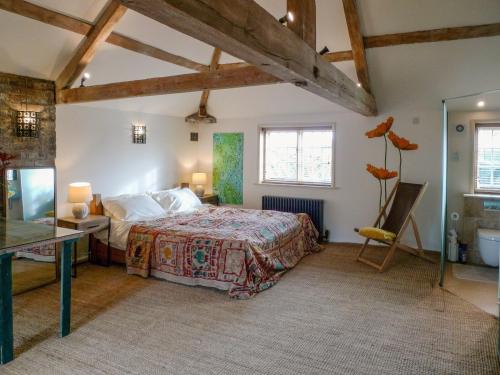 een slaapkamer met een bed, een bureau en ramen bij The Coach House in Syston