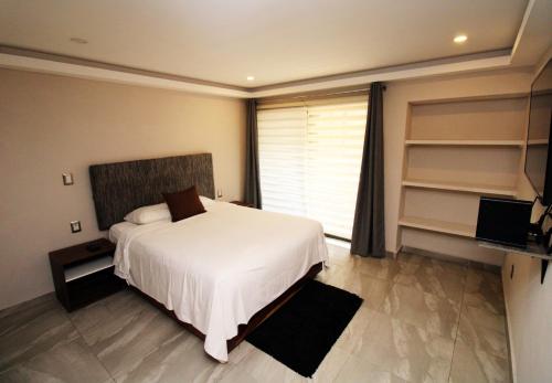 a bedroom with a white bed and a large window at OSLO 5 in Mexico City