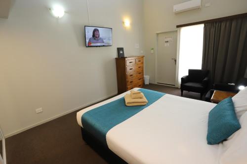 a bedroom with a bed and a chair and a television at Kallangur Motel in Kallangur