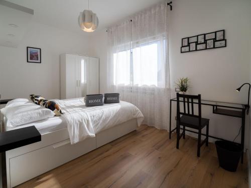 a white bedroom with a bed and a chair at Casa Felicità in Udine