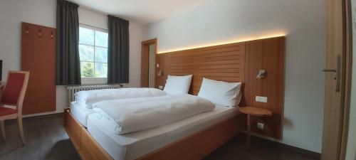 a bedroom with a large white bed and a window at Gasthof Edelweiss in Tires