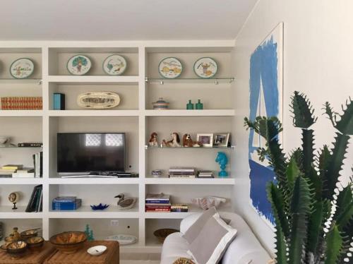 salon z białą półką i telewizorem w obiekcie Appartamento signorile, luminosissima vista mare w mieście Fregene