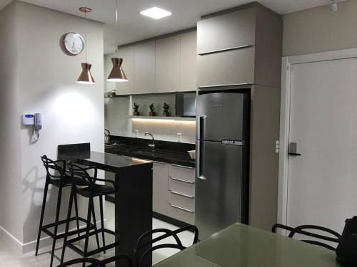 cocina con nevera, mesa y sillas en Apartamento requintado com vista para o mar- Casagrande 202, en Bombinhas
