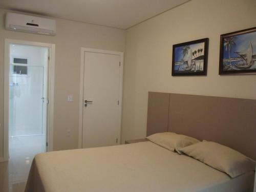 a bedroom with a bed and two pictures on the wall at Apartamento requintado com vista para o mar- Casagrande 202 in Bombinhas