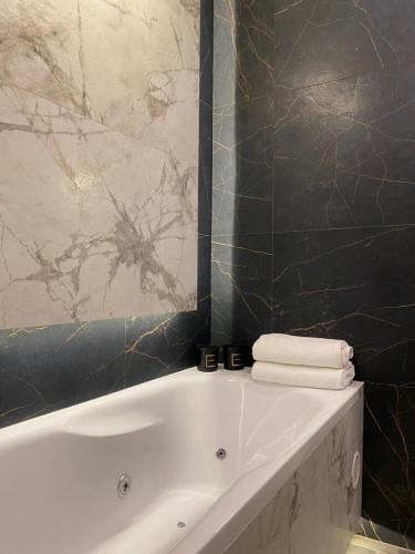 a bathroom with a white tub and a black wall at Family & Business Sauna Apartments Sienkiewicza Wesoła No 5 Centrum Downtown - 2 Bedroom with Private Sauna, Bath with Hydromassage, Parking - NEW! in Kielce