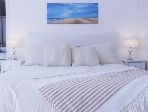 a white bedroom with a white bed with two lamps at 5C Departamento de dos ambientes, por escalera. in Mar del Plata