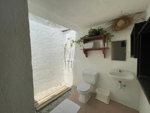 a bathroom with a toilet and a sink and a window at Quinta Feliz Troncones in Troncones