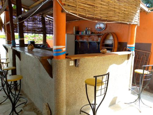 una cocina al aire libre con columnas naranjas y taburetes en Auberge Cœur Océan, en Joal-Fadiout