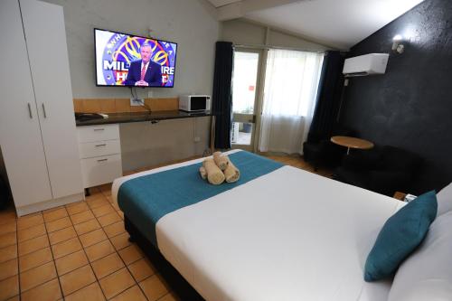 a hotel room with a bed with a teddy bear on it at Kallangur Motel in Kallangur