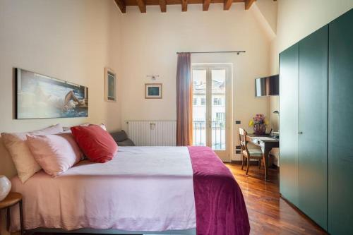 1 dormitorio con cama con almohadas rojas y escritorio en Duomo Apartment CIR 017029-CNI-00186, en Brescia