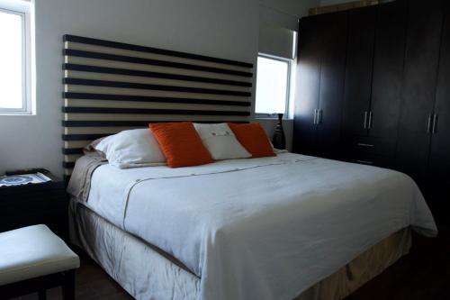 1 dormitorio con 1 cama grande con almohadas de color naranja y blanco en Habitación confortable dentro departamento Natura, en Ciudad de México