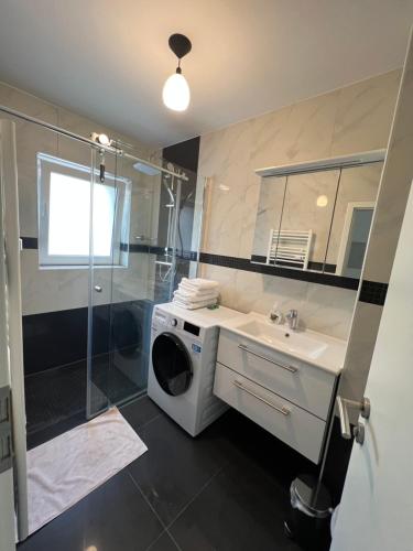 ein Badezimmer mit einer Waschmaschine, einem Waschbecken und einer Dusche in der Unterkunft Wunderschöne Unterkunft mit Terrasse - 24h7t Checkin in Karlsruhe