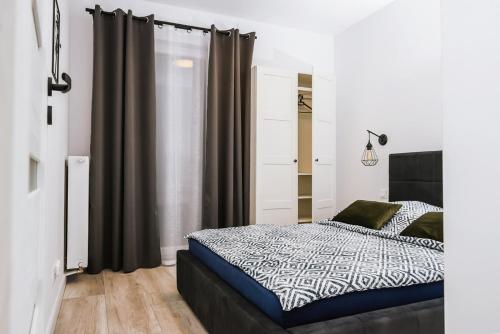 a bedroom with a black and white bed and curtains at Mazurski Apartament in Szczytno