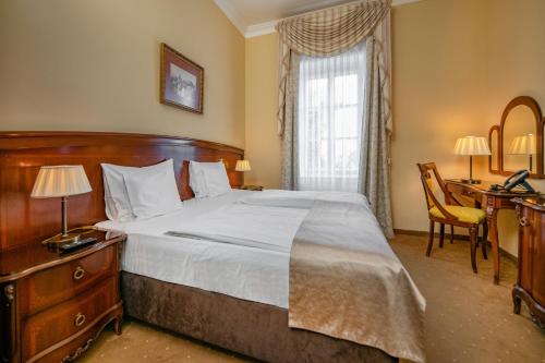 a bedroom with a large bed with a desk and a window at La Contessa Castle Hotel in Szilvásvárad