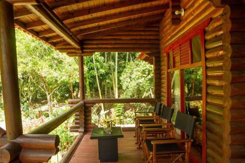 a wooden porch of a log cabin with tables and chairs at Eco Cabañas San Lorenzo in La Mesa
