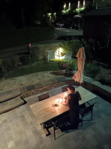 a woman sitting at a table in a backyard at night at B&B En face du Marronnier in Cornimont