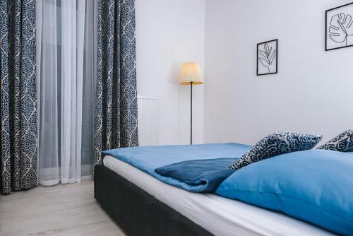 a bedroom with a bed with blue sheets and curtains at Mazurski Apartament 2 in Szczytno
