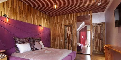 a bedroom with a purple bed and wooden walls at Four Seasons In Carpathians in Migovo