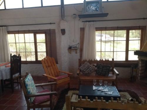 ein Wohnzimmer mit einem Tisch, Stühlen und Fenstern in der Unterkunft Tuminica Lodge - Chalet de montaña en Suesca in Suesca