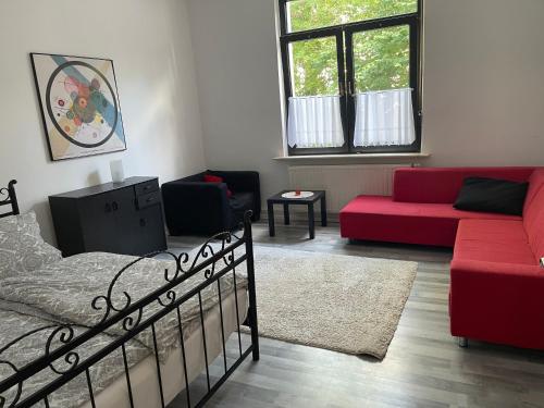 ein Schlafzimmer mit einem Bett und einem roten Sofa in der Unterkunft Ferienwohnung Zentral in Kassel in Kassel