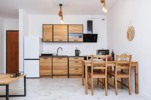 a kitchen with a wooden table and wooden cabinets at Mazurski Apartament 2 in Szczytno
