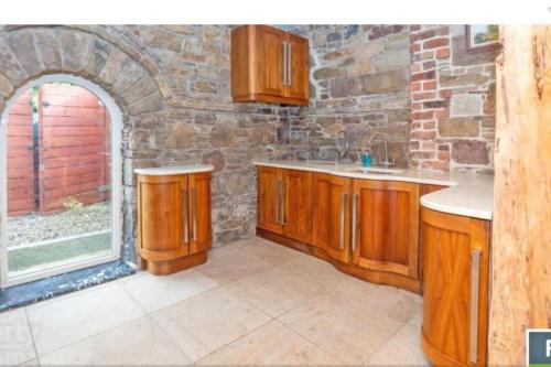 una cocina con armarios de madera y una pared de piedra. en 2 Bed Sandstone Residence, en Newport