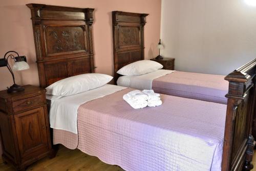 two beds in a hotel room with towels on them at b&b CASCINA SORTINA Country House in Ozzano Monferrato