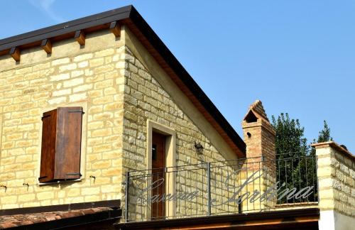 a brick building with a balcony with a window at b&b CASCINA SORTINA Country House in Ozzano Monferrato