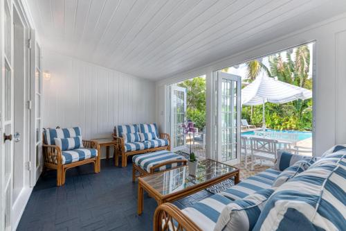 西棕櫚灘的住宿－Maison Papillon Vacation Home，一个带蓝色和白色椅子的门廊和游泳池