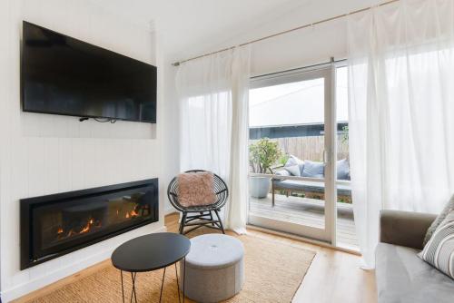 a living room with a fireplace and a television at By The Seaside in Mornington