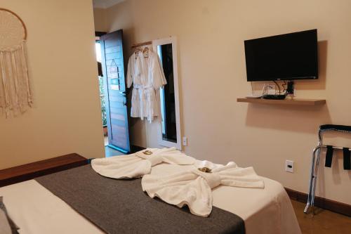a room with a bed with white robes on it at Pousada Lua Clara in Alto Paraíso de Goiás