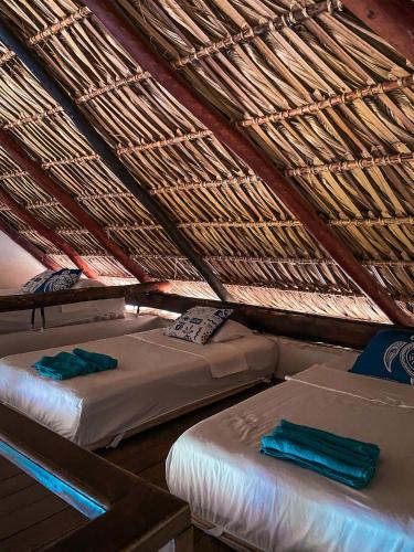 two beds in a room with a roof at Hotel Maya Jade in Monterrico