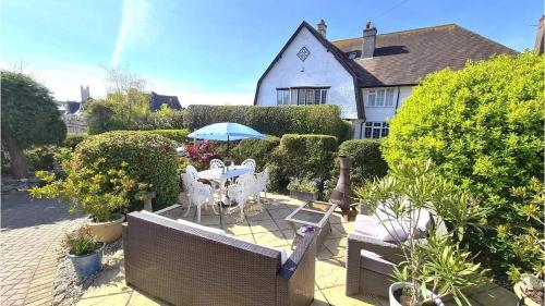 a patio with a table and chairs and an umbrella at Malindi bed and breakfast in Exmouth