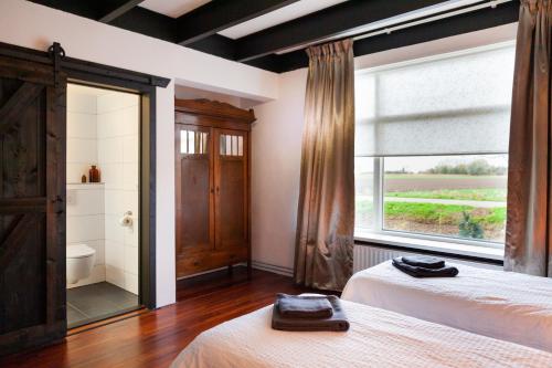 a bedroom with two beds and a large window at Pait's Laand Bed & Breakfast in Overschild