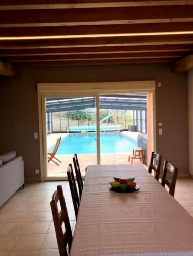 une salle à manger avec une table et une piscine dans l'établissement Gîte la bergerie, piscine chauffée,, à Couzon