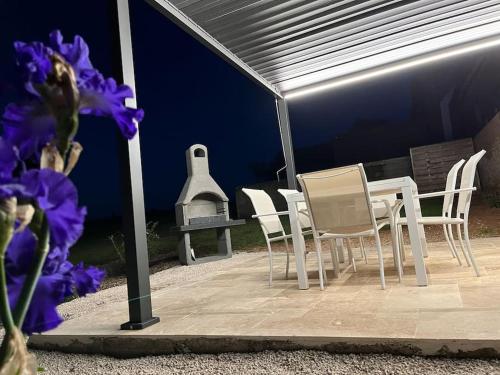 a patio with a table and chairs and a grill at Gîte la bergerie, piscine chauffée, in Couzon