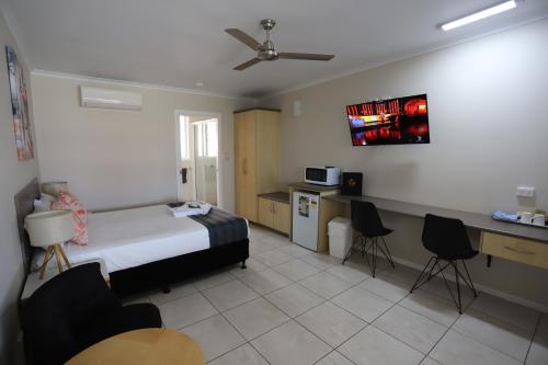 a bedroom with a bed and a table and chairs at Tropic Coast Motel in Mackay