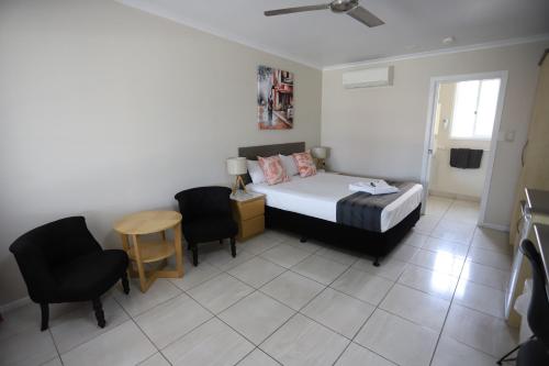 a bedroom with a bed and a table and chairs at Tropic Coast Motel in Mackay