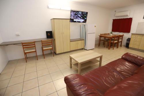 a living room with a couch and a kitchen at Tropic Coast Motel in Mackay