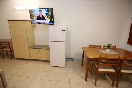 a kitchen with a refrigerator and a table and a tv at Tropic Coast Motel in Mackay