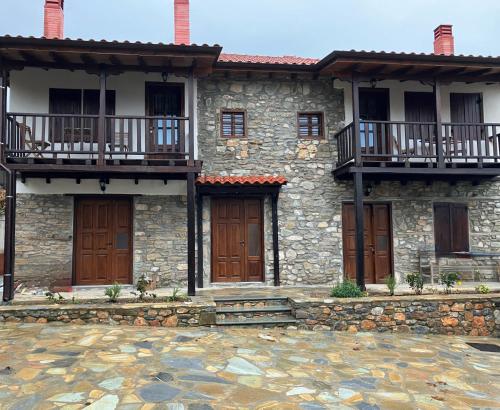 a stone house with wooden doors and a balcony at Melofegaro Guesthouse in Palaios Panteleimon