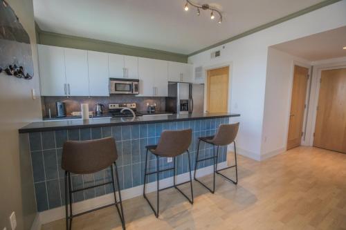 a kitchen with a counter and chairs in a room at Designer Downtown Condo Suite - Splendid View in Des Moines