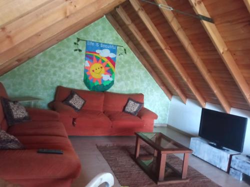 ein Wohnzimmer mit einem roten Sofa und einem TV in der Unterkunft Cucunuba por Siempre in El Salitre