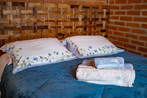 a bed with two pillows and towels on it at Chales Canto da Natureza in São Bento do Sapucaí