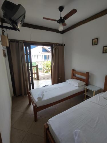 a bedroom with two beds and a balcony with a fan at Brisa Maresias in Maresias