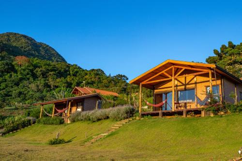 a house on top of a grassy hill at Chales Canto da Natureza in São Bento do Sapucaí