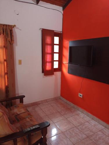 a living room with a red wall with a flat screen tv at Alojamiento Familiar Nobili in Puerto Iguazú